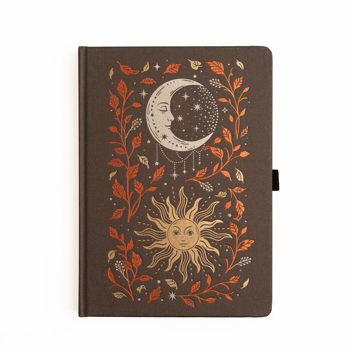 Dark buckram notebook with foiled celestial sun and moon design surrounded by autumn leaves